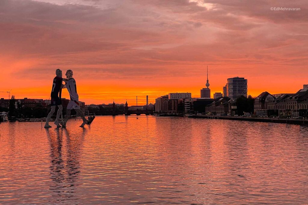 sunset of Berlin from a view of the Berlin TV tower and the reflection of Molecule Man in the river.