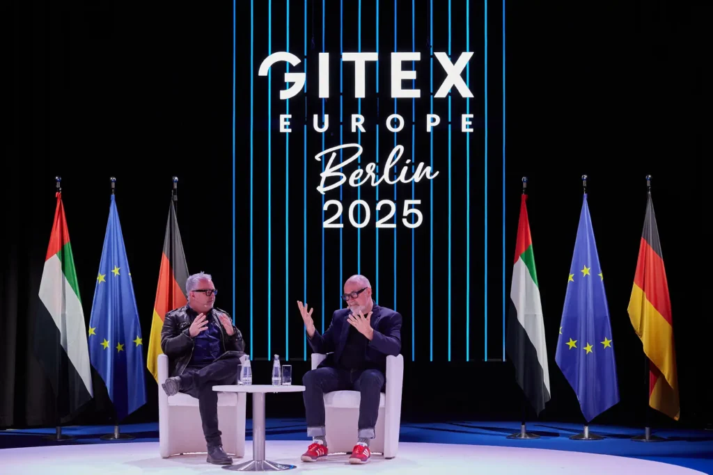 2 men sitting on the stage of Gitex Europe and giving a talk to the public