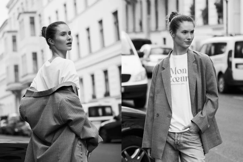 Schwarz-Weiß-Foto einer Frau in eleganter Straßenkleidung in Berlin-Mitte. Im Hintergrund sind klassische Mitte-Architektur und geparkte Autos zu sehen.