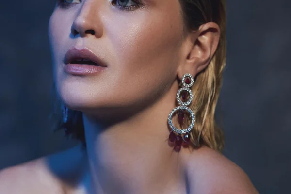 A model named Jennifer Gilmore with wet, straight, blonde hair and smoky eye makeup. She is wearing jewellery from Chopard. Disarray has a tree circle that is kind of dropping. She is posing in the camera like her shoulders pushing to the front like kind of fashion style. And from the back, I put the soft blue light, which is separating the model from the background. And this jewelry photoshooting publish it in the official Arabian jewelry issue.