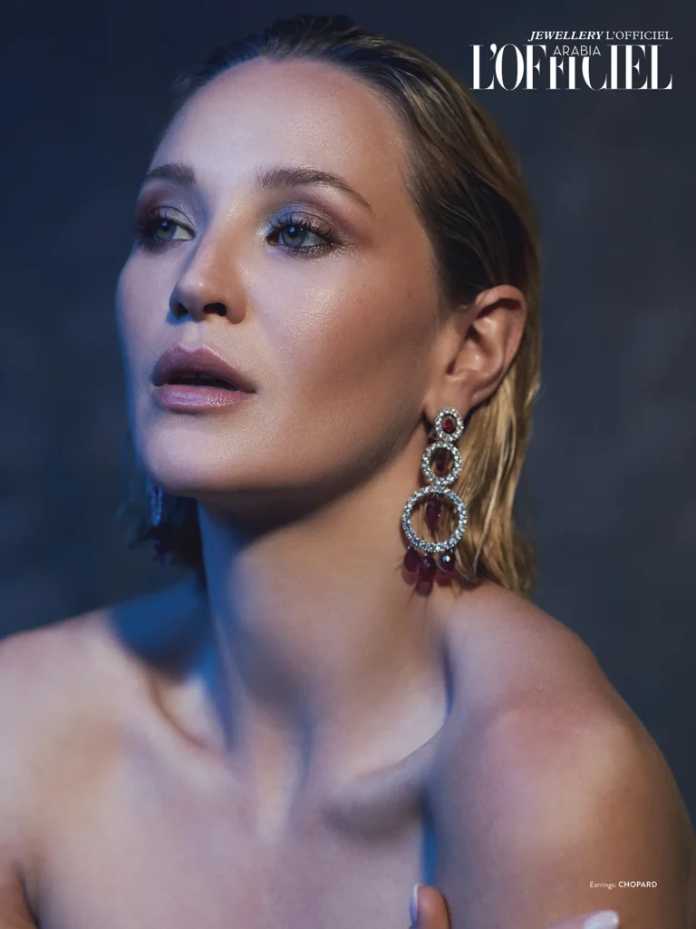 A model named Jennifer Gilmore with wet, straight, blonde hair and smoky eye makeup. She is wearing jewellery from Chopard. Disarray has a tree circle that is kind of dropping. She is posing in the camera like her shoulders pushing to the front like kind of fashion style. And from the back, I put the soft blue light, which is separating the model from the background. And this jewelry photoshooting publish it in the official Arabian jewelry issue.